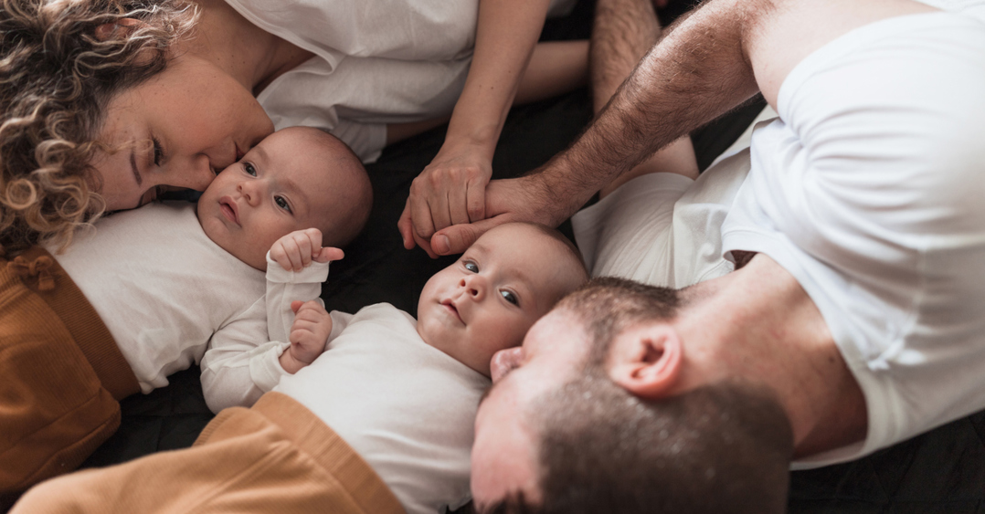 Happy parents cuddling with their newborn sons